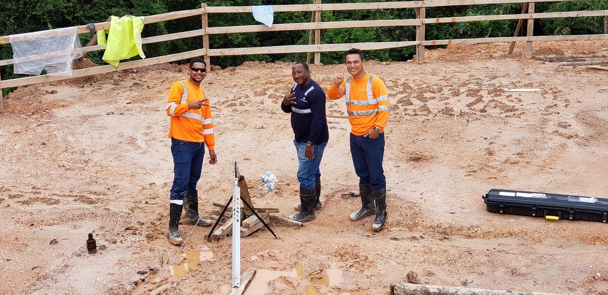 Field team over borehole tripod, cleaning wireline
