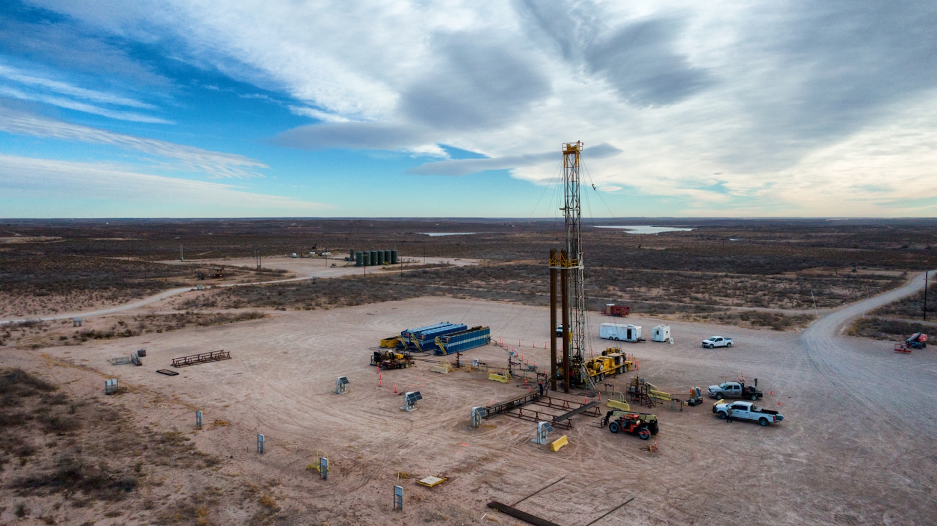 Drone view of an oil or gas drill fracking rig pad with trucks and equipment